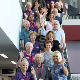 A group photos of lots of volunteers stood on a staircase.