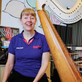 A woman sat beside a harp.