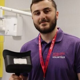 A man smiling at the camera while holding a VR headset.