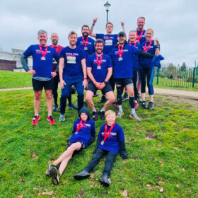 A group of people in Royal Free Charity t-shirts wearing medals, outdoors in a park.