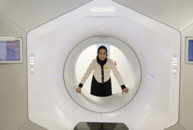 A radiographer looking through the inner circle of a white radiotherapy machine.