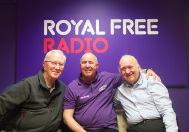 Three men sat in front of a purple wall that says 'Royal Free Radio'