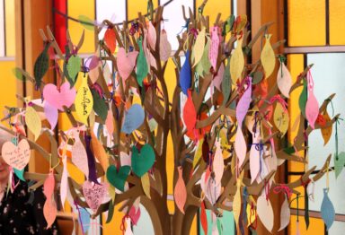 A craft tree covered in small pieces of colourful paper to resemble leaves on which prayers are written.