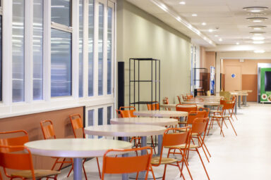 White tables and orange chairs in a hospital restaurant.