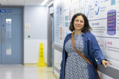 A woman in a blue dress standing in a hospital corridor.