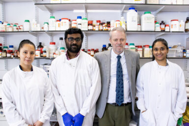 A group of researchers, including Richard Stratton, standing together in a laboratory inside the Pears Building at Royal Free Hospital, surrounded by lab equipment and scientific instruments.