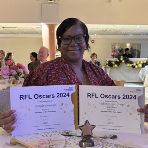 Woman smiling while holding two certificates.