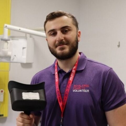 A man smiling at the camera while holding a VR headset.