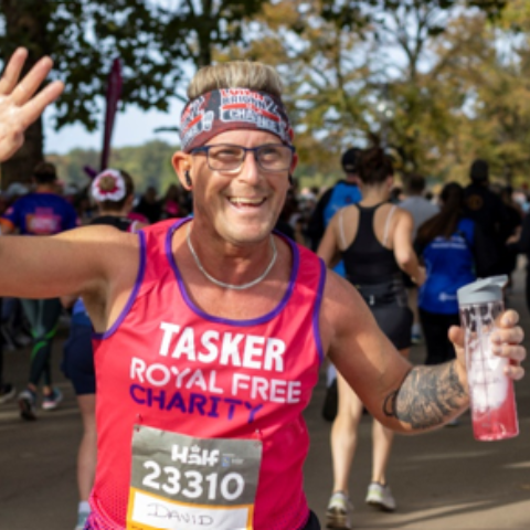 Participant wearing a Royal Free Charity bib number, running in a charity race event outdoors, captured mid-stride with determination and focus.