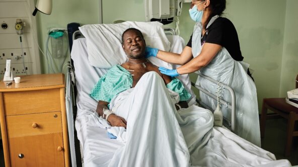 Man lying in hospital bed receiving a massage from a complementary massage therapist.