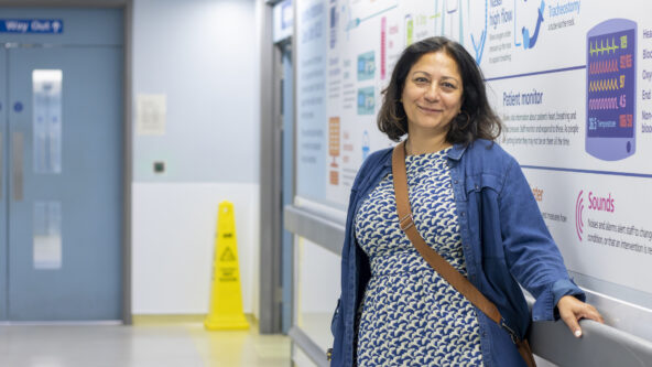 A woman in a blue dress standing in a hospital corridor.
