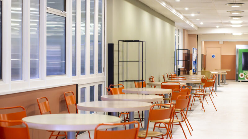 White tables and orange chairs in a hospital restaurant.