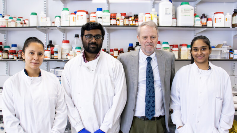 A group of researchers, including Richard Stratton, standing together in a laboratory inside the Pears Building at Royal Free Hospital, surrounded by lab equipment and scientific instruments.