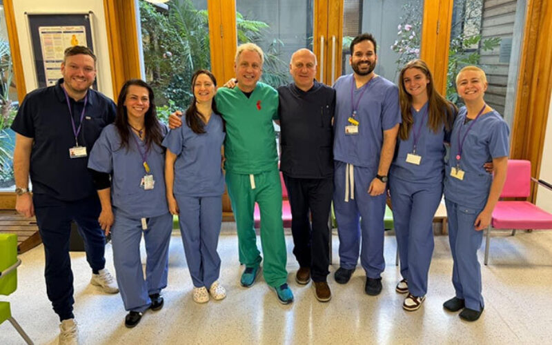 A group of people in scrubs standing in a row in a calmly lit room.