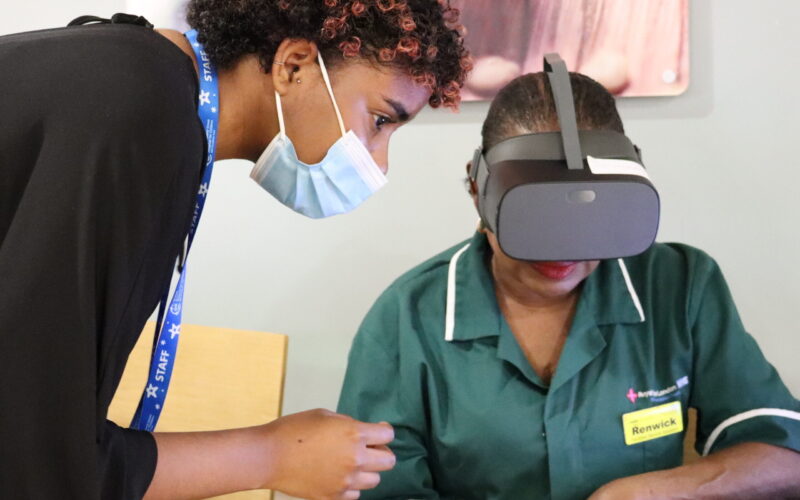Woman helping a member of NHS staff with a VR headset