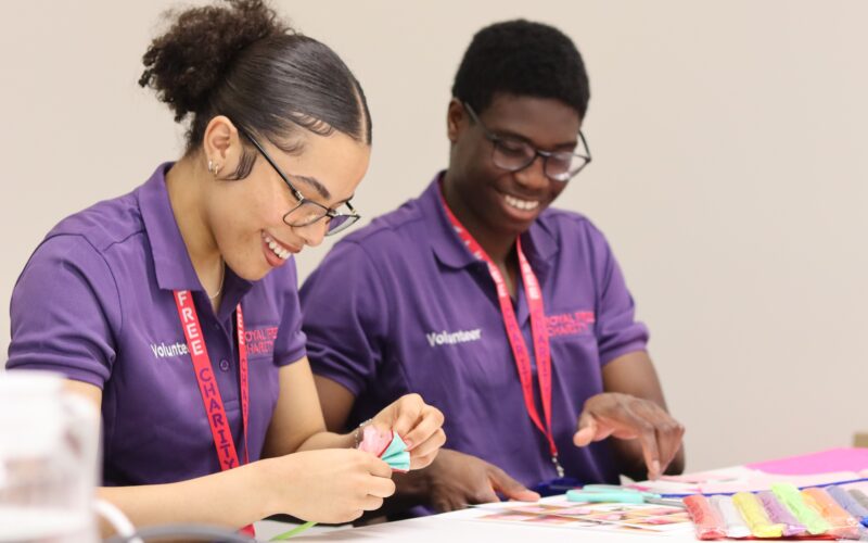 Two young volunteers doing crafts while sat at a table.
