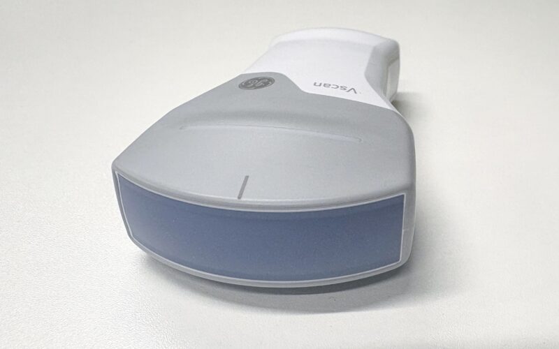 A grey pocket-sized ultrasound scanner on a table.