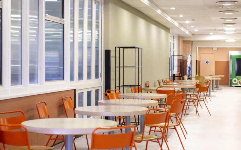 White tables and orange chairs in a hospital restaurant.