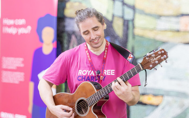 Man standing up playing an acoustic guitar.