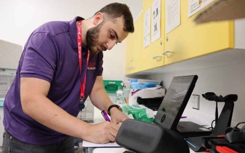 A man writing on paper next to a VR headset.