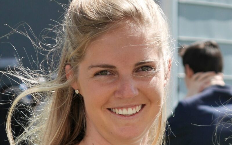 Miranda Filmer, smiling at her graduation ceremony, wearing a graduation gown.