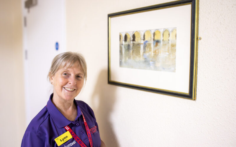 Woman standing by a piece of art work in the hospital corridor.