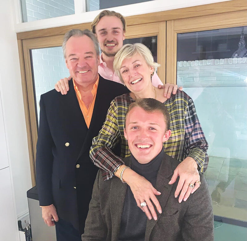 A group of people with their arms around each other, smiling at the camera.
