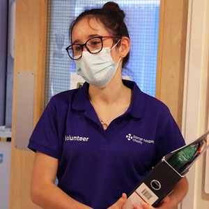 Volunteer in mask standing in from of door in hospital corridor