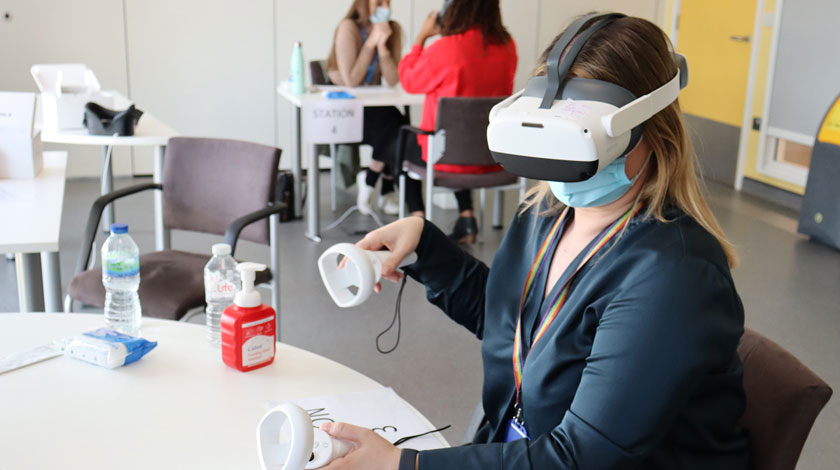 Women wearing a virtual reality headset and joysticks in each hand