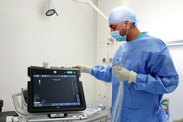 A doctor in full scrubs next to a monitor 