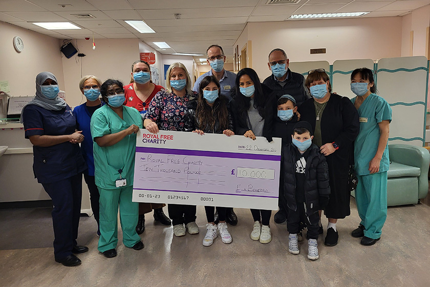 A group in PPE clothing, celebrating together holding a cheque for £10,000