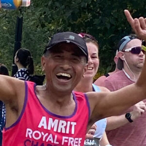 Close up of man raising his hands and smiling while running in a park with others. 