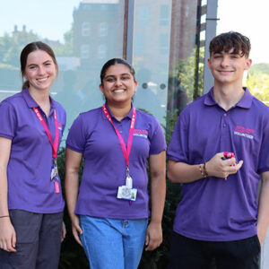 Three people in RFC volunteering t-shirts stood outside beside a building.
